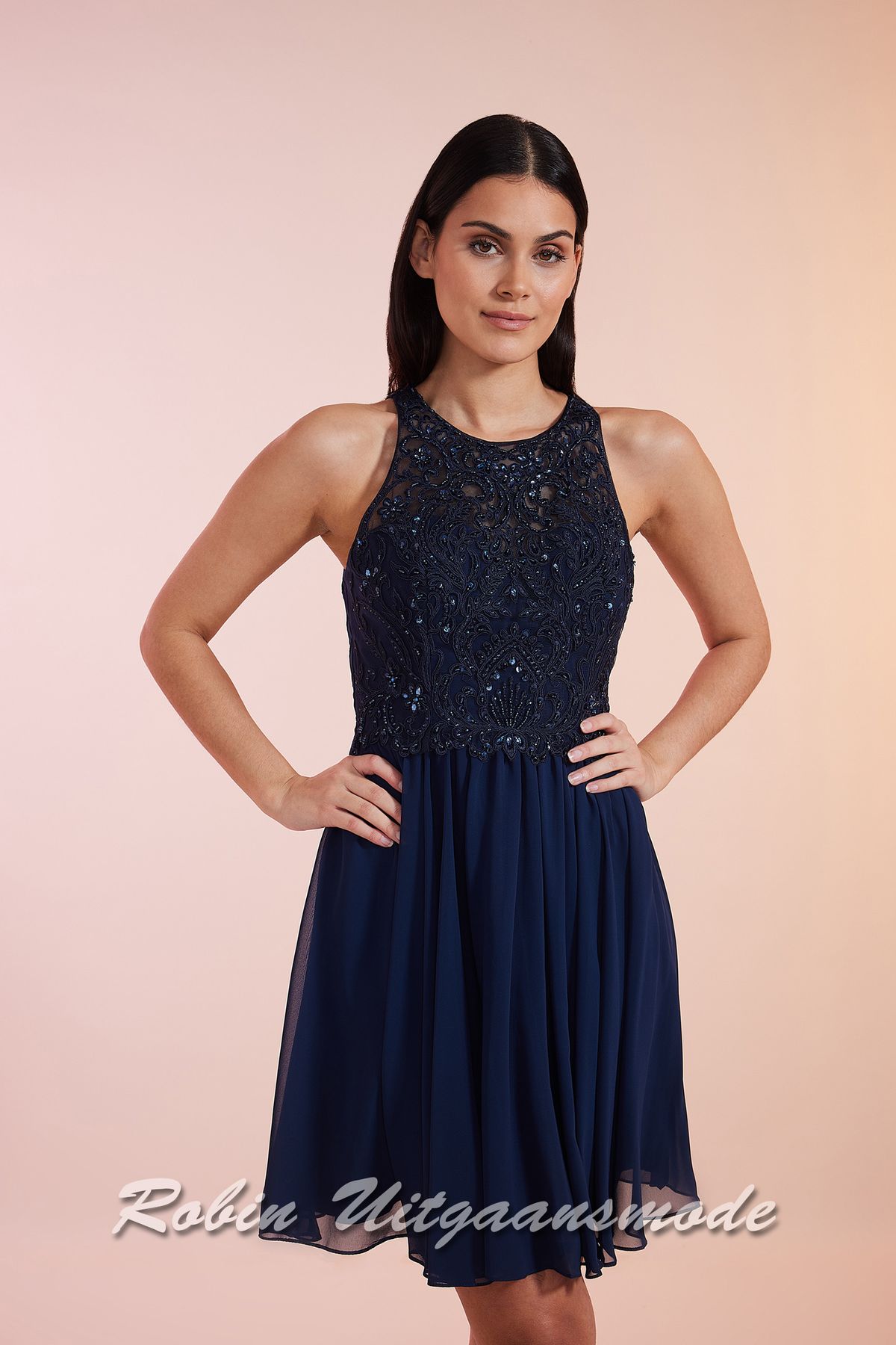Close-up van de Navy blauwe cocktailjurk met hooggesloten kanten lijfje, blote schouders en een geplooide chiffon rok tot net boven de knie