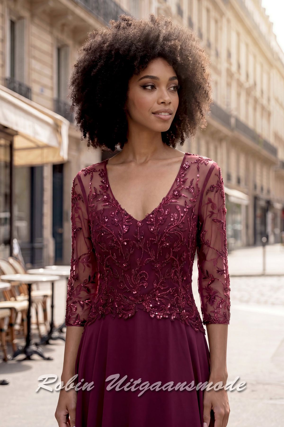 Close-up van de Bordeauxrode geklede avondjurk met kanten lijfje, driekwart mouwen, een V-hals en sluikvallende chiffon rok met plooien