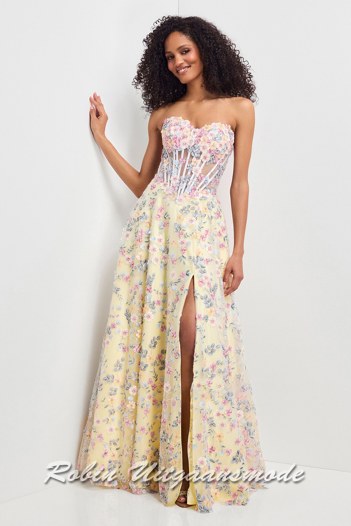 Strapless gele galajurk geheel versierd met bloemen, een strapless top met heartshape bustelijn, semi transparantie taille en lange rok met hoge split