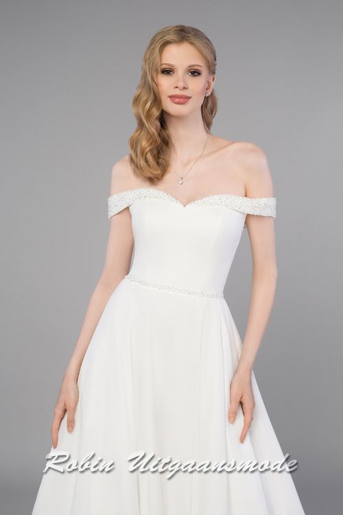 Close-up van de Trouwjurk met glitter off-shoulder halslijn, aansluitend lijfje met vetersluiting en A-lijn rok met split