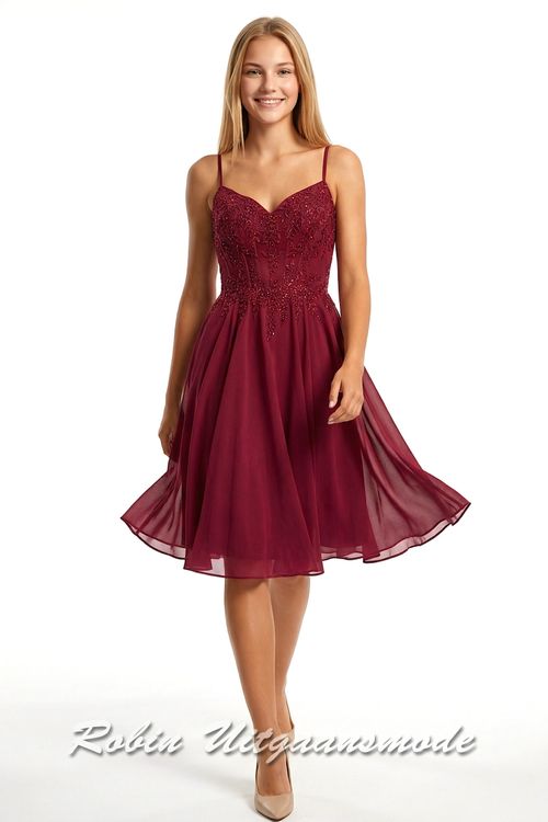Korte bordeauxrode galajurk met versierd kanten lijfje, smalle bandjes recht doorlopend over de open rug en licht geplooide chiffon rok tot net over de knie.