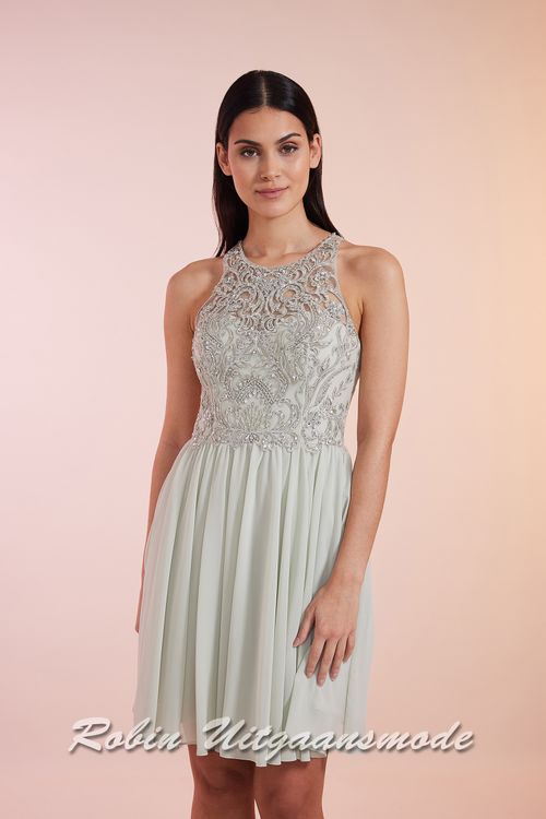 Close-up van de Mint groen cocktailjurk met hooggesloten kanten lijfje, blote schouders en een geplooide chiffon rok tot net boven de knie