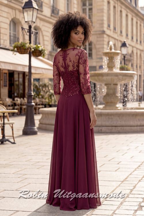 Achterkant van de Bordeauxrode geklede avondjurk met kanten lijfje, driekwart mouwen, een V-hals en sluikvallende chiffon rok met plooien