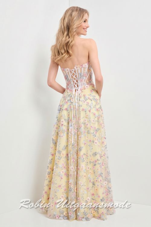 Achterkant van de Strapless gele galajurk geheel versierd met bloemen, een strapless top met heartshape bustelijn, semi transparantie taille en lange rok met hoge split